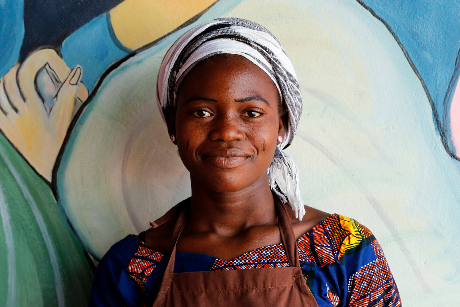 Portrait d’une jeune femme portant des scarifications avec un sourire complice au Bénin en 2013