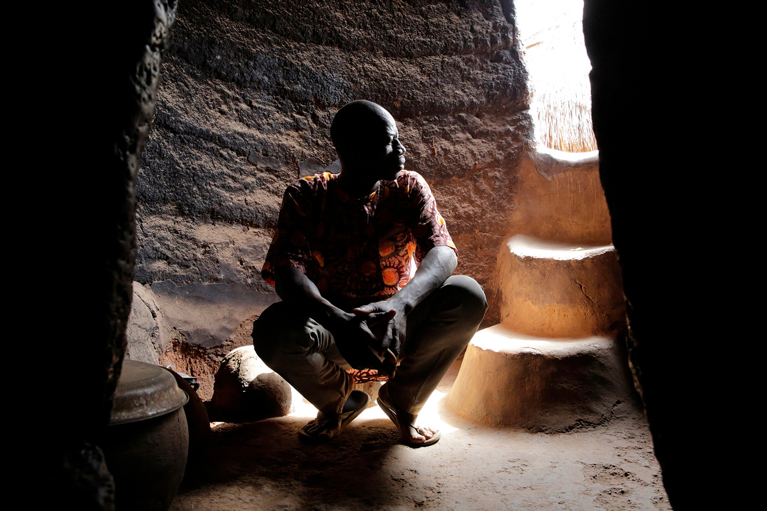 Homme dans un tata au Bénin en 2017, éclairé par un clair-obscur