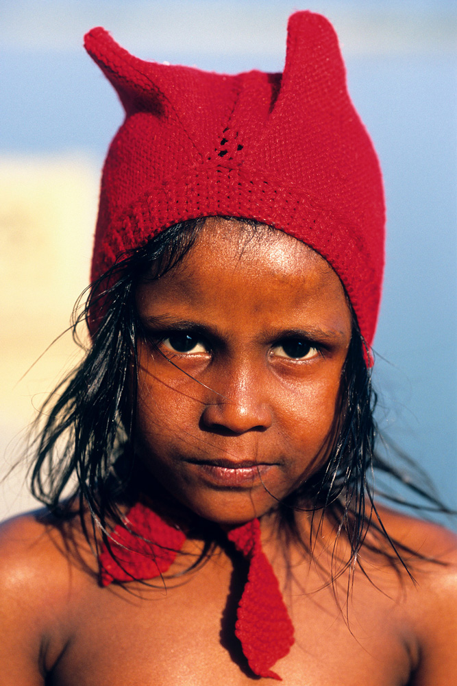 Fillette portant un bonnet rouge au bord du Gange en Inde en 2005.