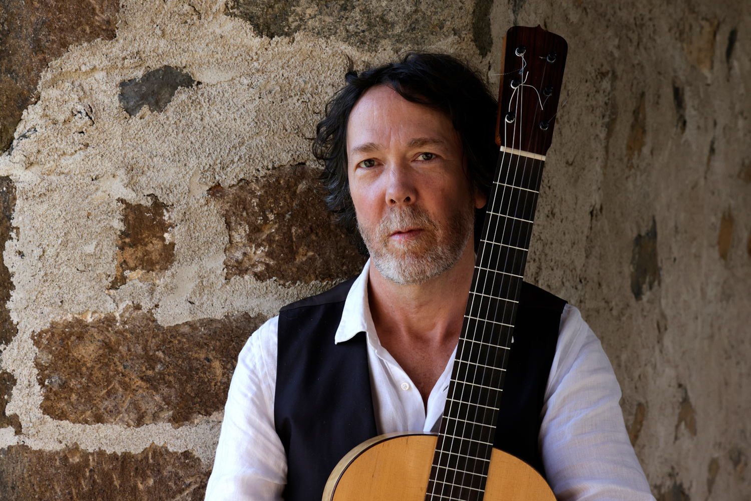 Mathias Duplessy tenant une guitare lors d’un shooting en 2024 pour Cavalcade Trio à Chanteuges