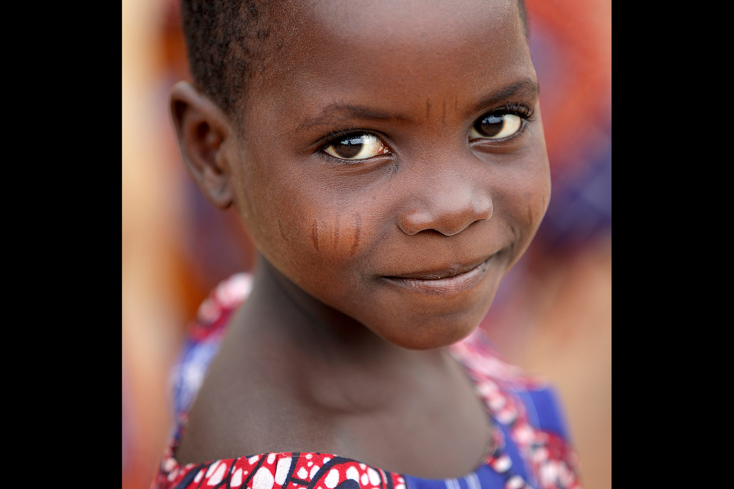 Portrait d’une jeune fille portant des scarifications et souriant au Bénin en 2011