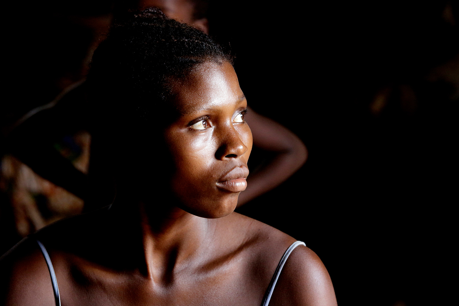 Jeune femme au Bénin en 2015 regardant vers l’horizon dans un jeu d’ombre et de lumière