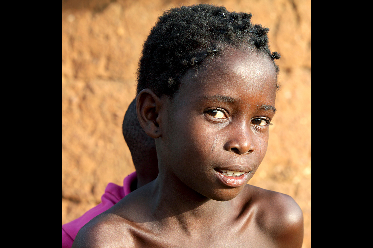 Portrait d’une jeune fille au Bénin en 2011 avec un sourire en coin et des scarifications