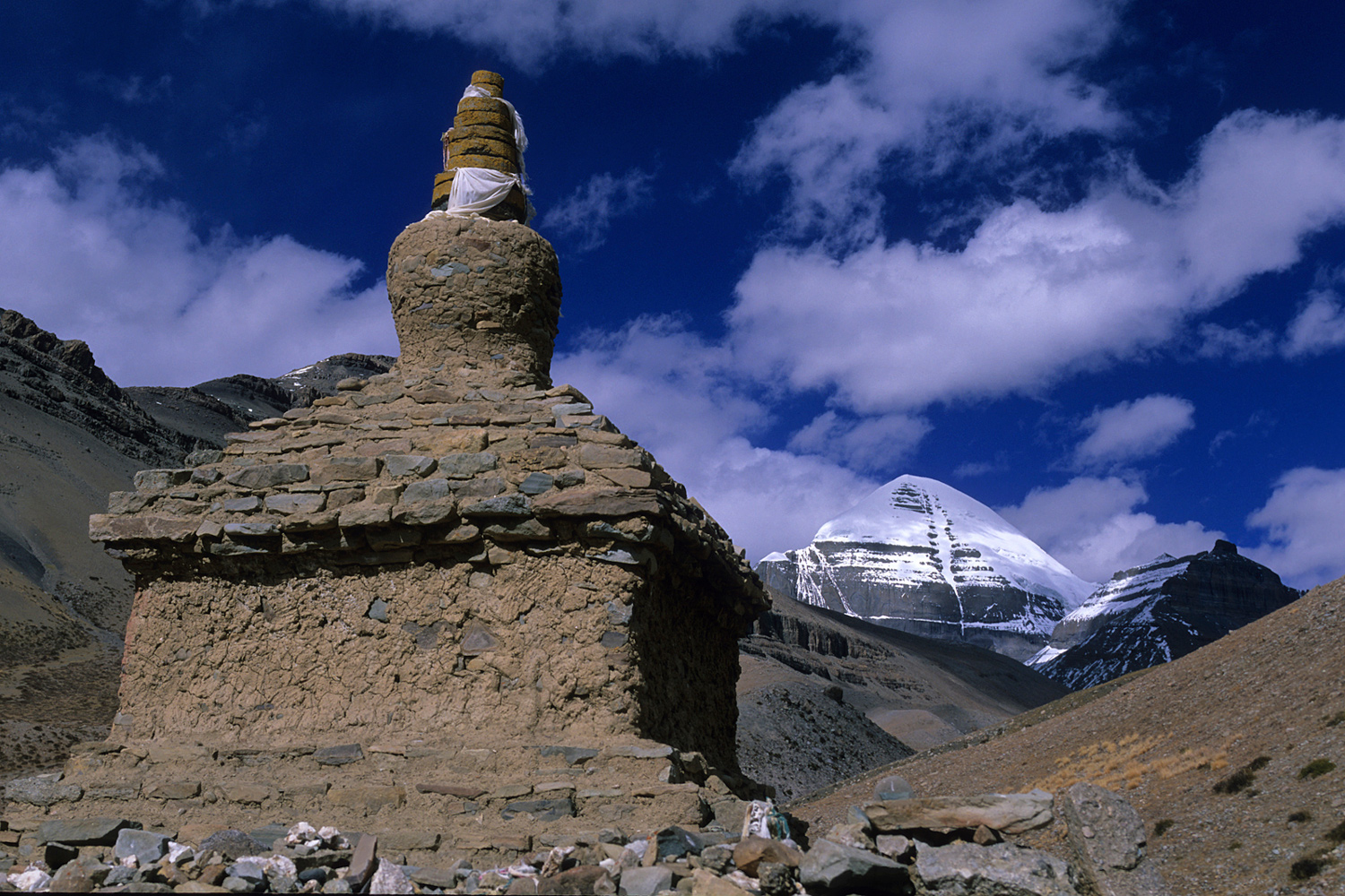 Chorten au premier plan avec le sommet enneigé du mont Kailash en arrière-plan au Tibet en 2004 partiellement couvert par des nuages au Tibet en 2004