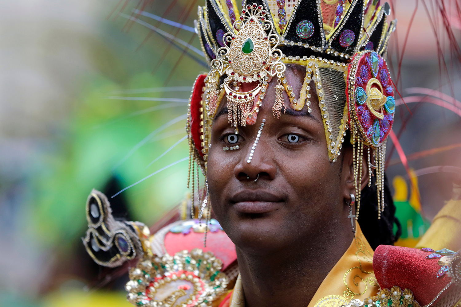Portrait d'un participant portant une grande coiffe traditionnelle ornée de bijoux et de perles.