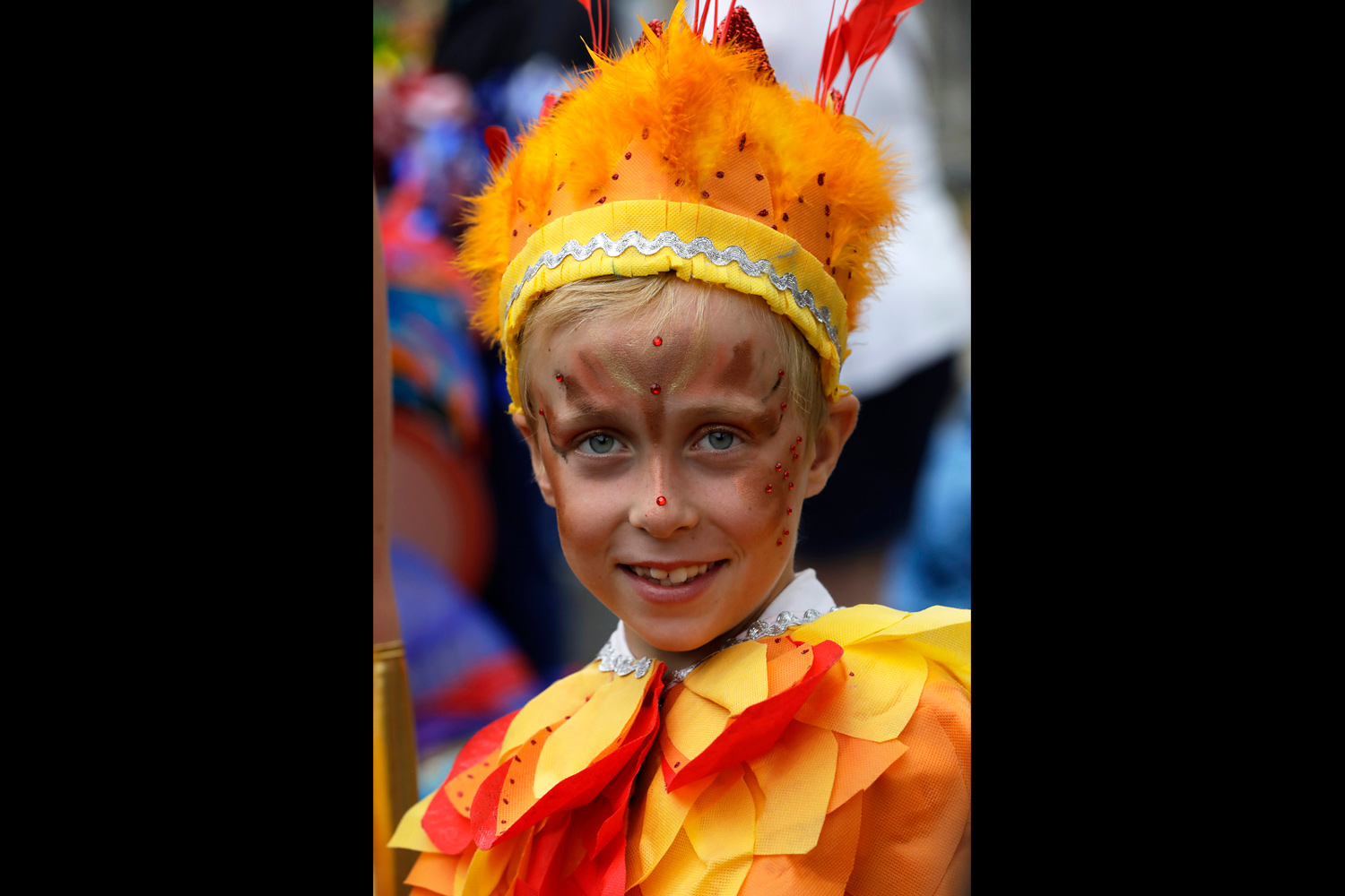 Portrait d'un enfant souriant portant une coiffe jaune et orange.