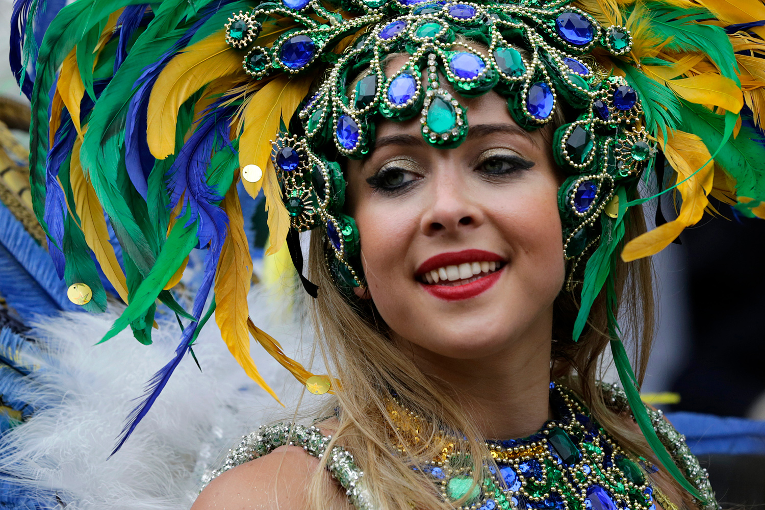 Portrait d'une danseuse coiffée d'une imposante coiffe verte, bleue et jaune.