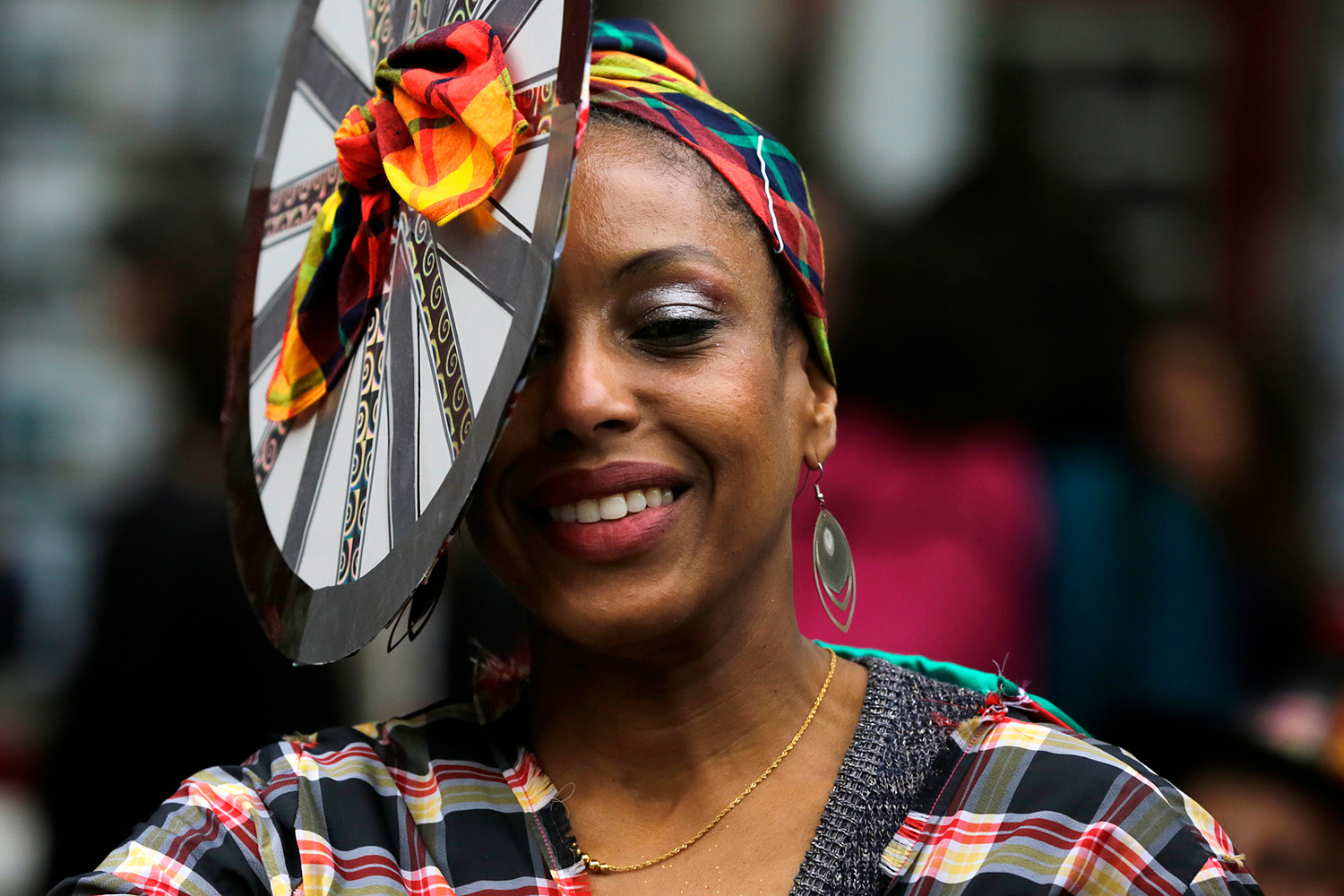 Portrait d'une participante souriante tenant un accessoire décoratif devant son visage pendant le Carnaval Tropical de Paris.