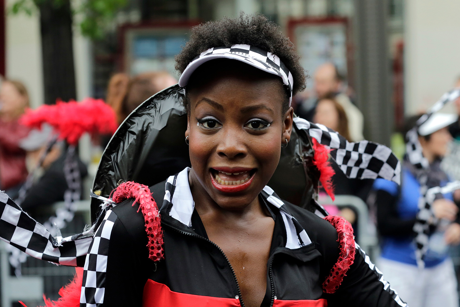 Portrait d'une danseuse souriante vêtue d'un costume noir, rouge et blanc.