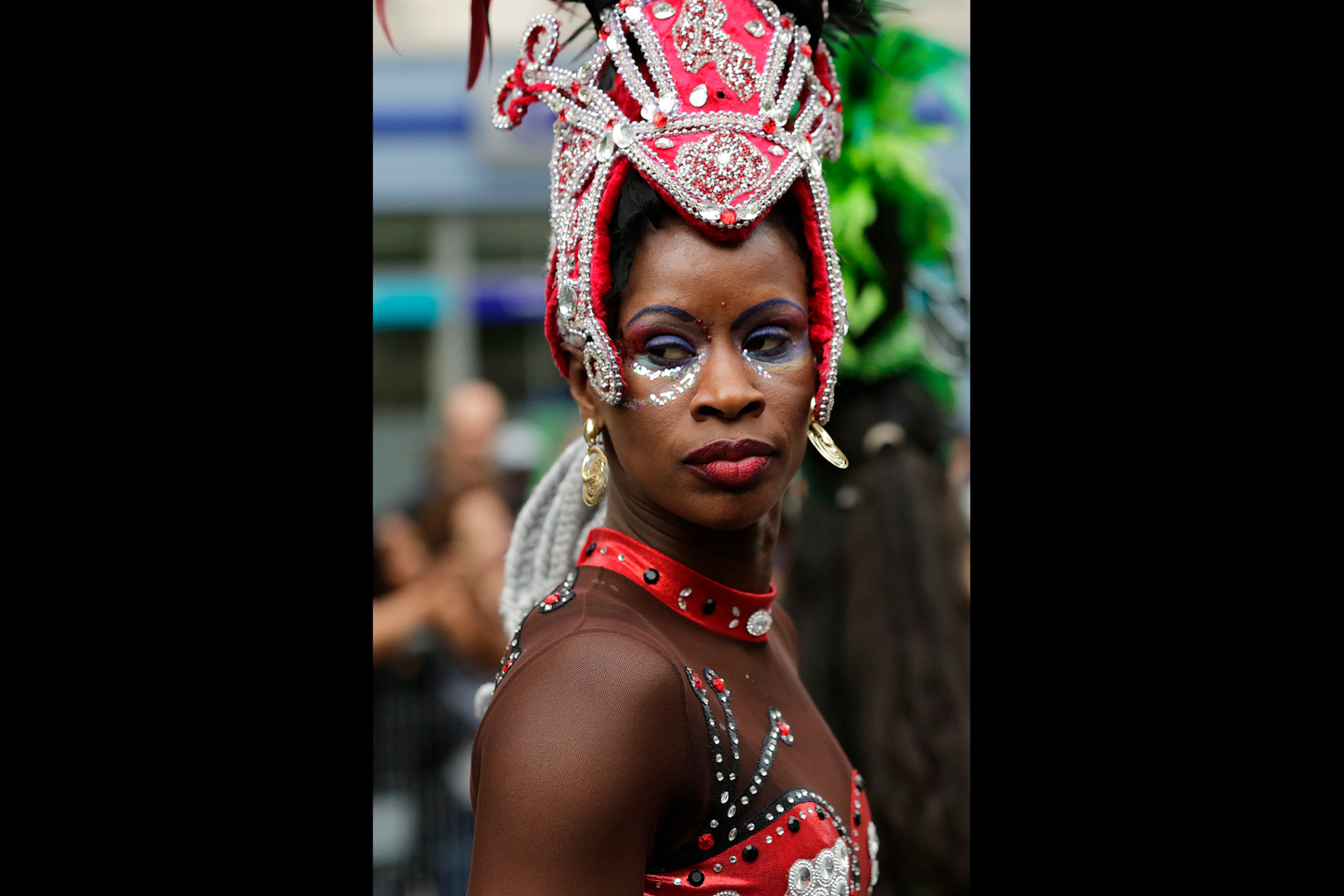 Portrait d'une danseuse portant une coiffe rouge et argent richement décorée.