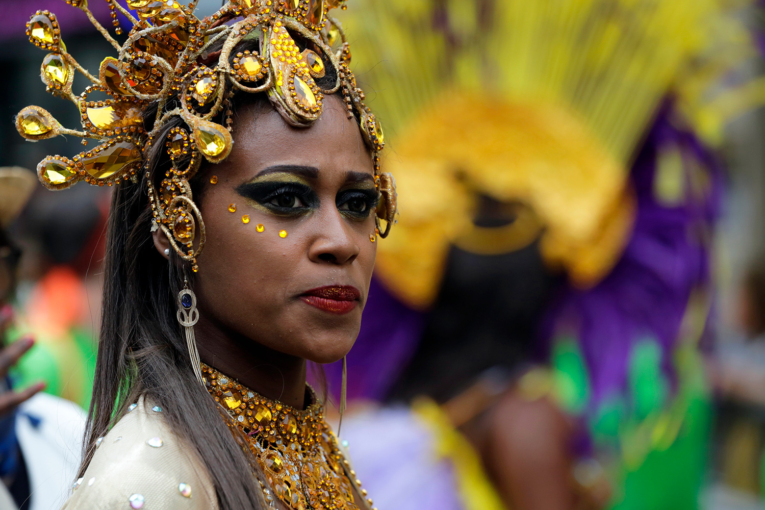 Portrait d'une participante portant une somptueuse coiffe dorée ornée de bijoux et de pierres.