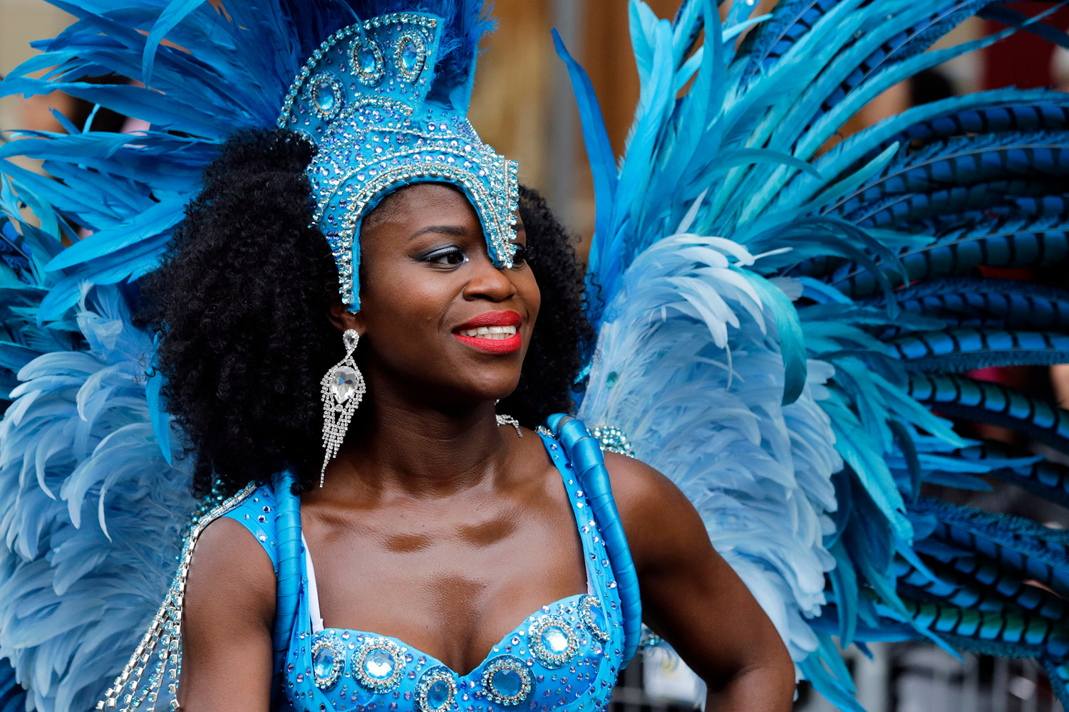 Danseuse portant un imposant costume bleu orné de plumes.