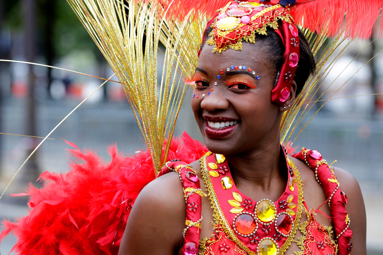 Portrait d'une danseuse souriante portant un costume rouge orné de plumes.
