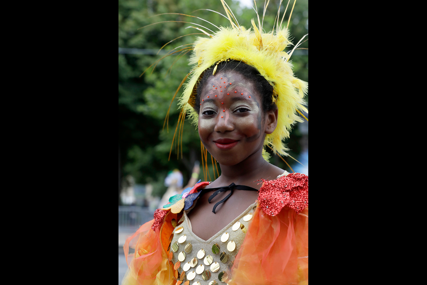 Portrait d'une jeune femme portant une coiffe jaune et un costume orange scintillant.