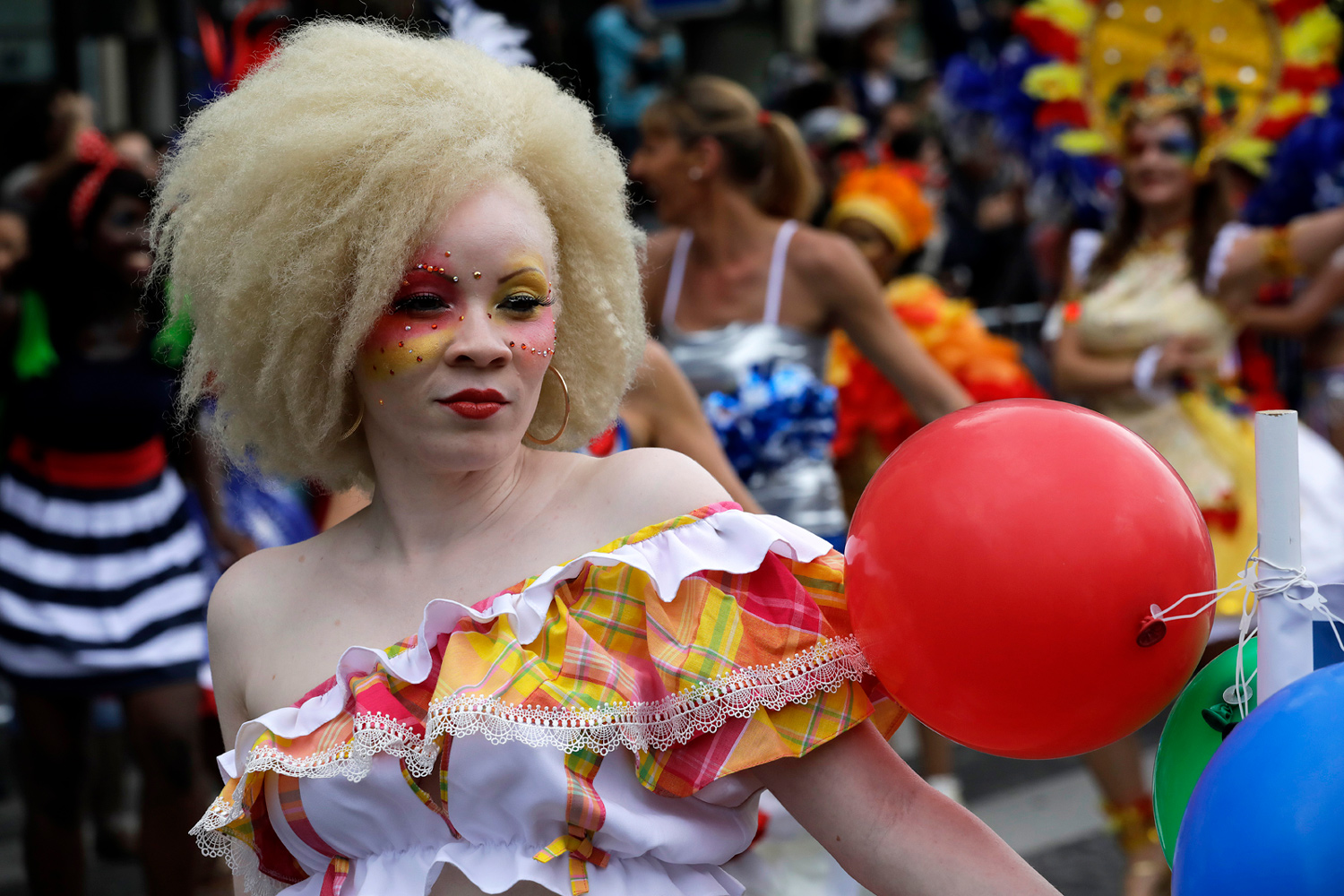 Portrait d'une participante costumée en clown tenant un ballon rouge.