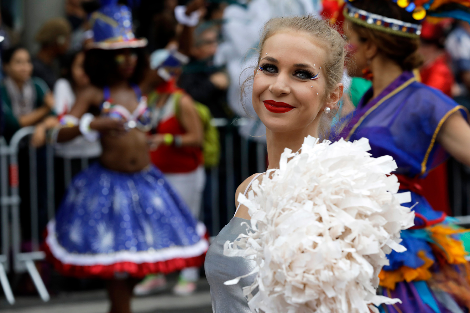Portrait d'une danseuse blonde souriant au public, vêtue d'une tenue blanche à plumes.
