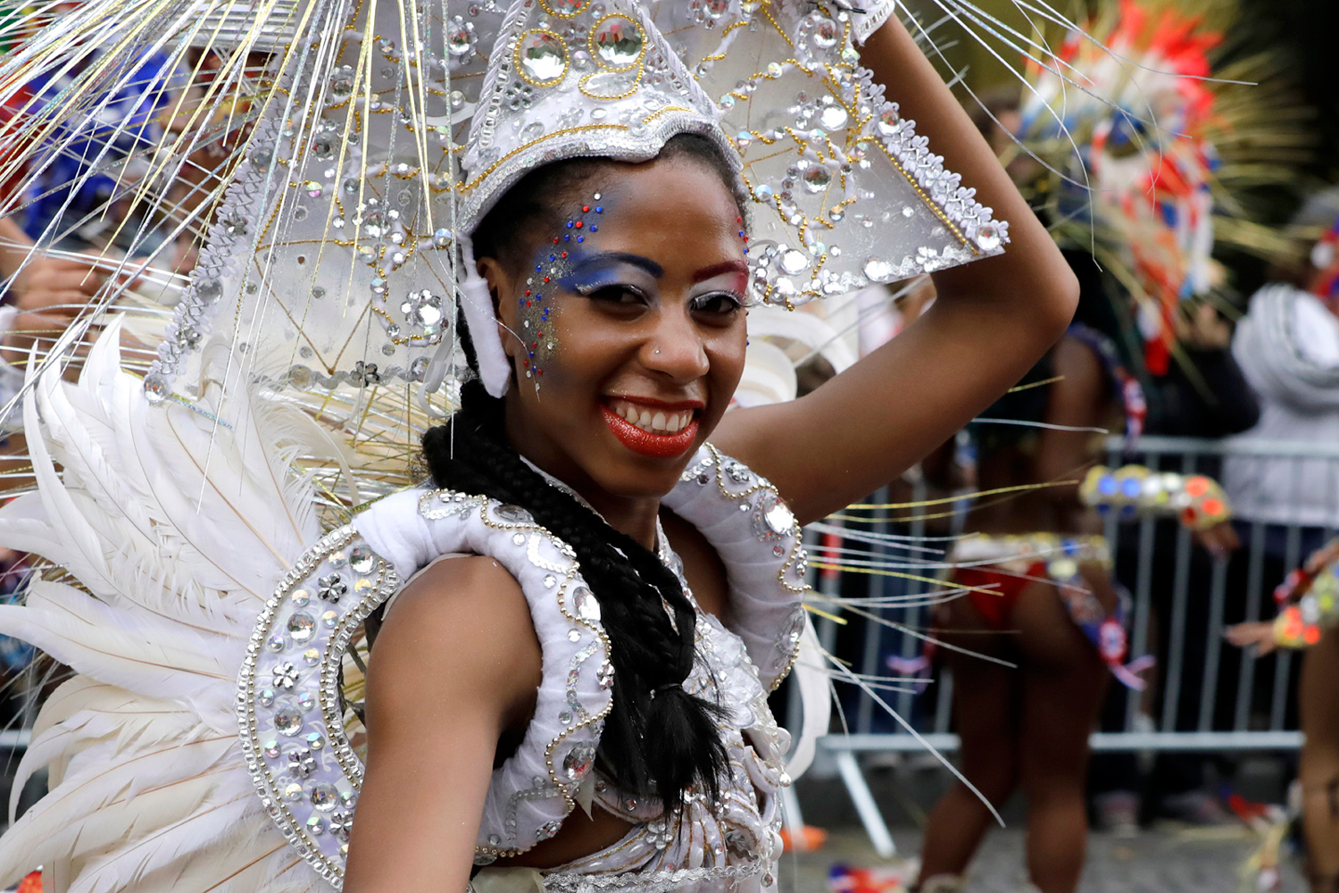 Portrait d'une danseuse souriante portant un costume blanc et une coiffe argentée.