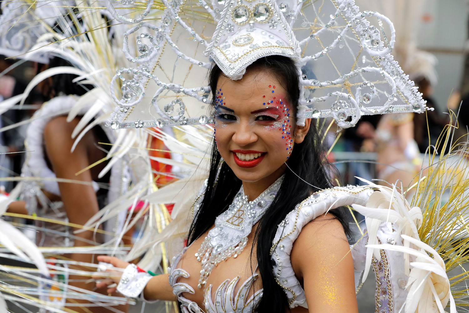 Portrait d'une danseuse souriante vêtue d'un costume blanc richement décoré.