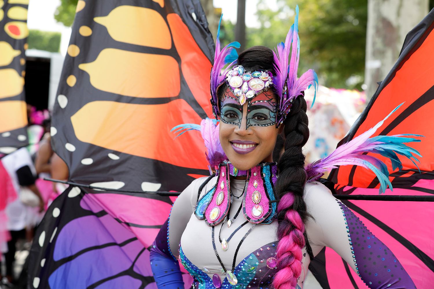 Portrait d'une danseuse souriante portant un costume de papillon aux grandes ailes colorées.