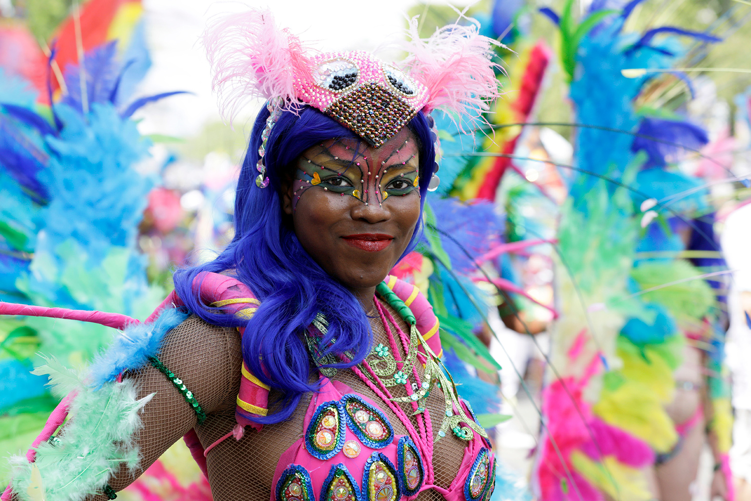 Portrait d'une danseuse portant une perruque violette et un costume multicolore à plumes.