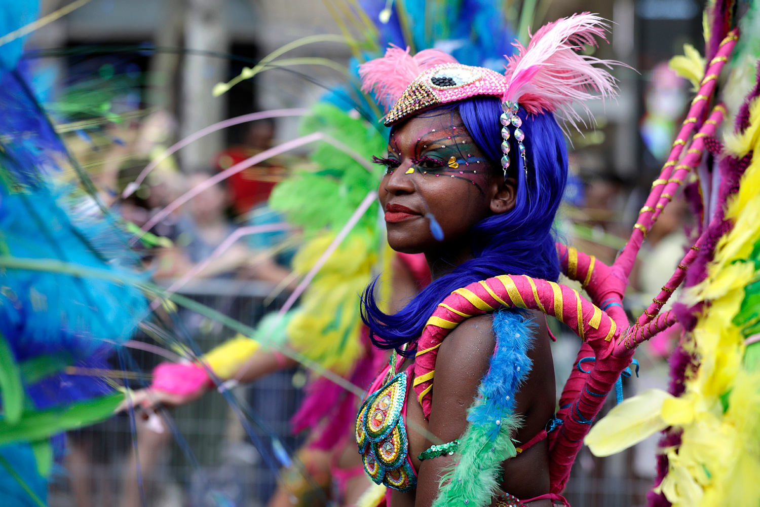 Portrait de profil d'une danseuse portant un costume aux plumes multicolores et un maquillage bleu.