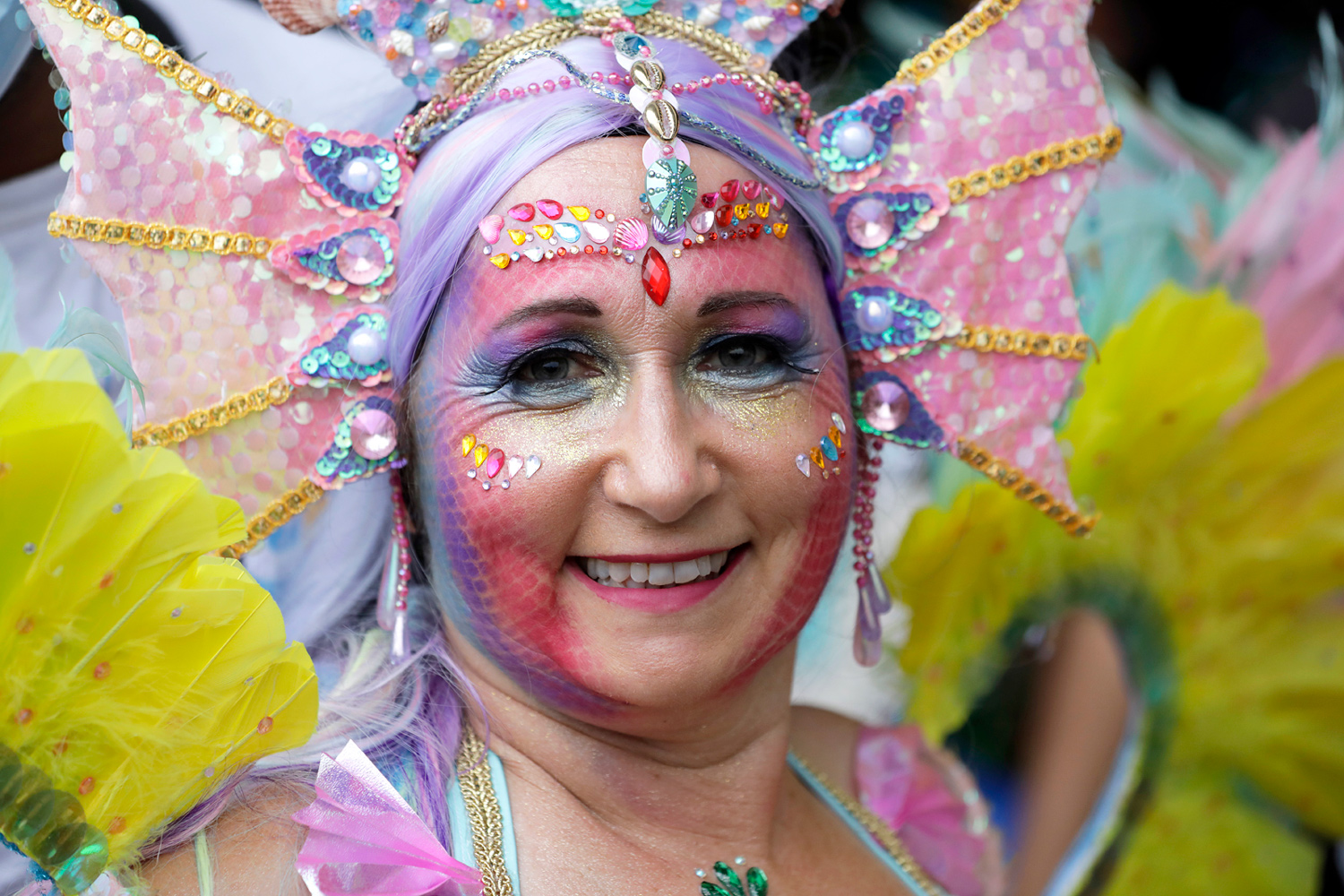 Portrait d'une danseuse aux cheveux violets portant une coiffe pastel décorée de coquillages et de plumes.