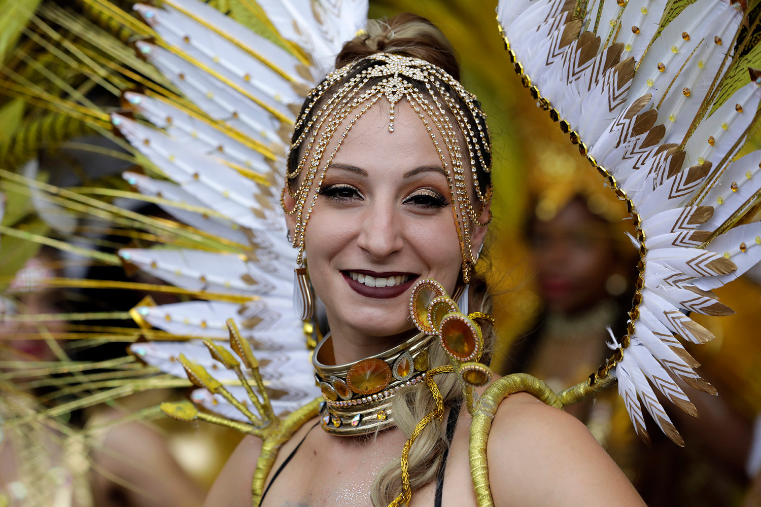 Portrait rapproché d'une danseuse souriante portant une coiffe blanche et dorée.