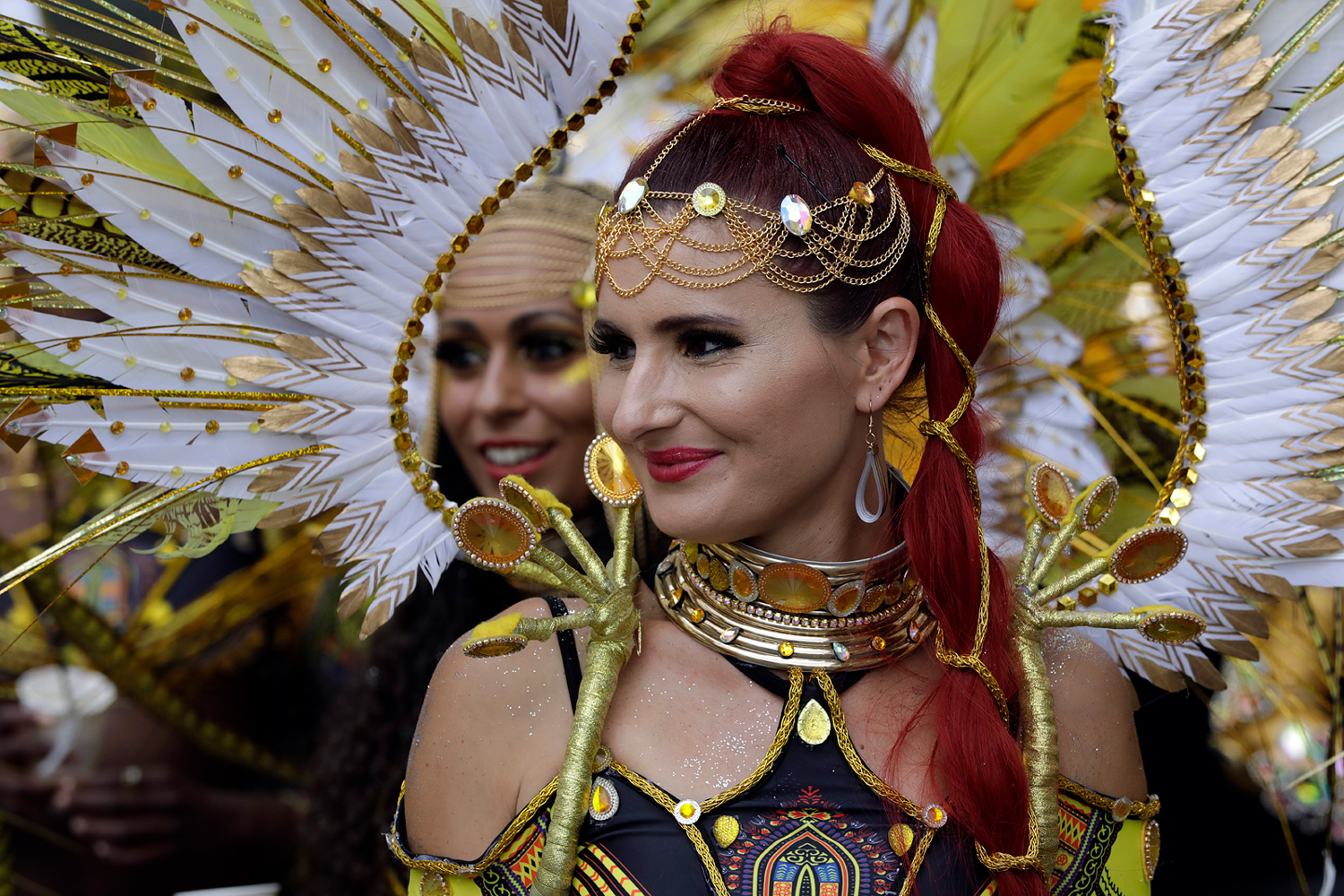 Portrait d'une danseuse rousse portant une grande coiffe blanche et dorée.