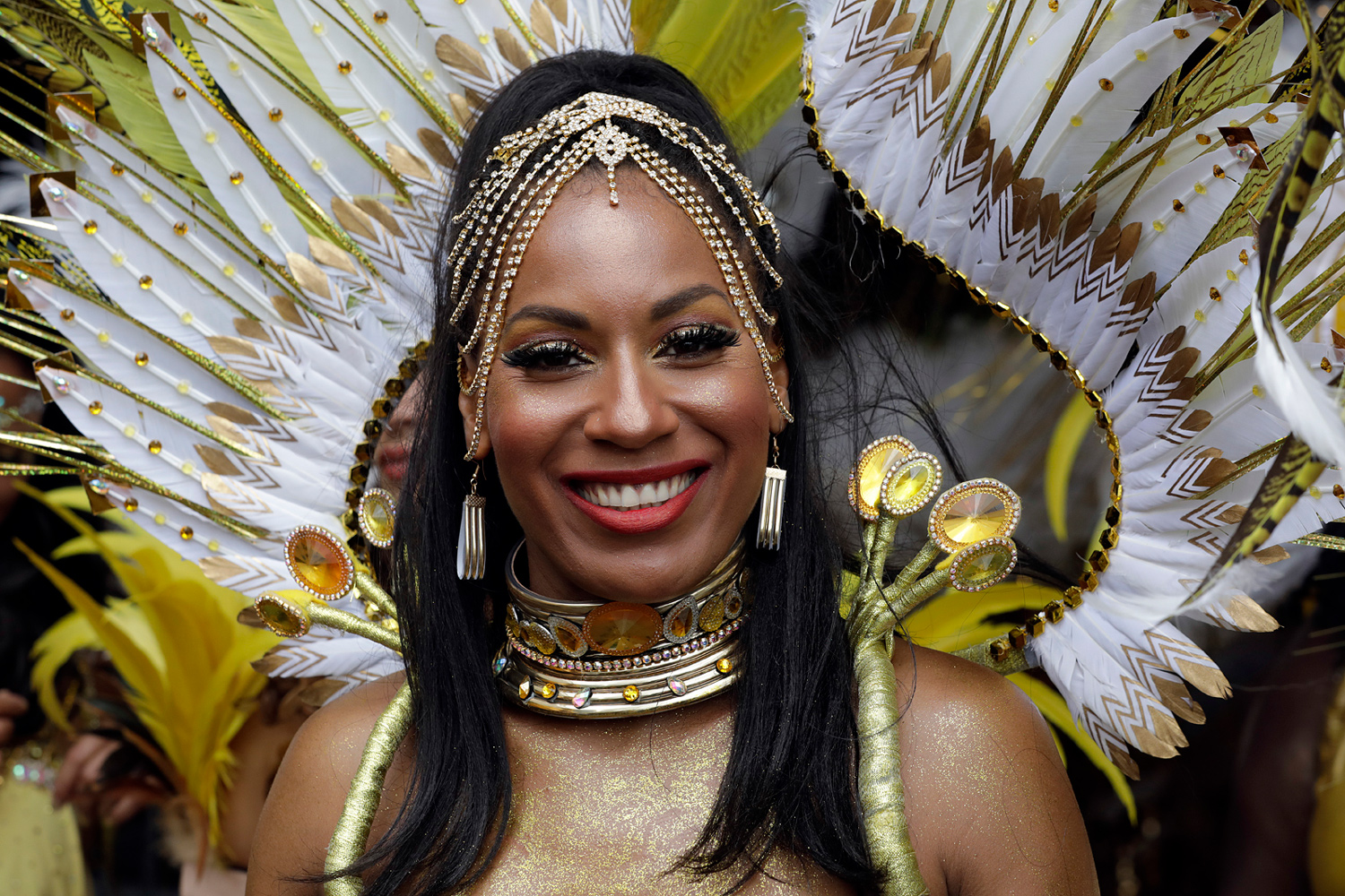 Portrait d'une danseuse souriante coiffée de longues tresses et d'une coiffe blanche et dorée.