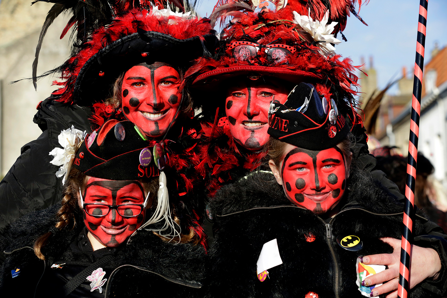 Groupe de carnavaleux vêtus de costumes noirs et rouges, maquillés de rouge avec des pois noirs, posant ensemble lors de la Bande de Bergues.