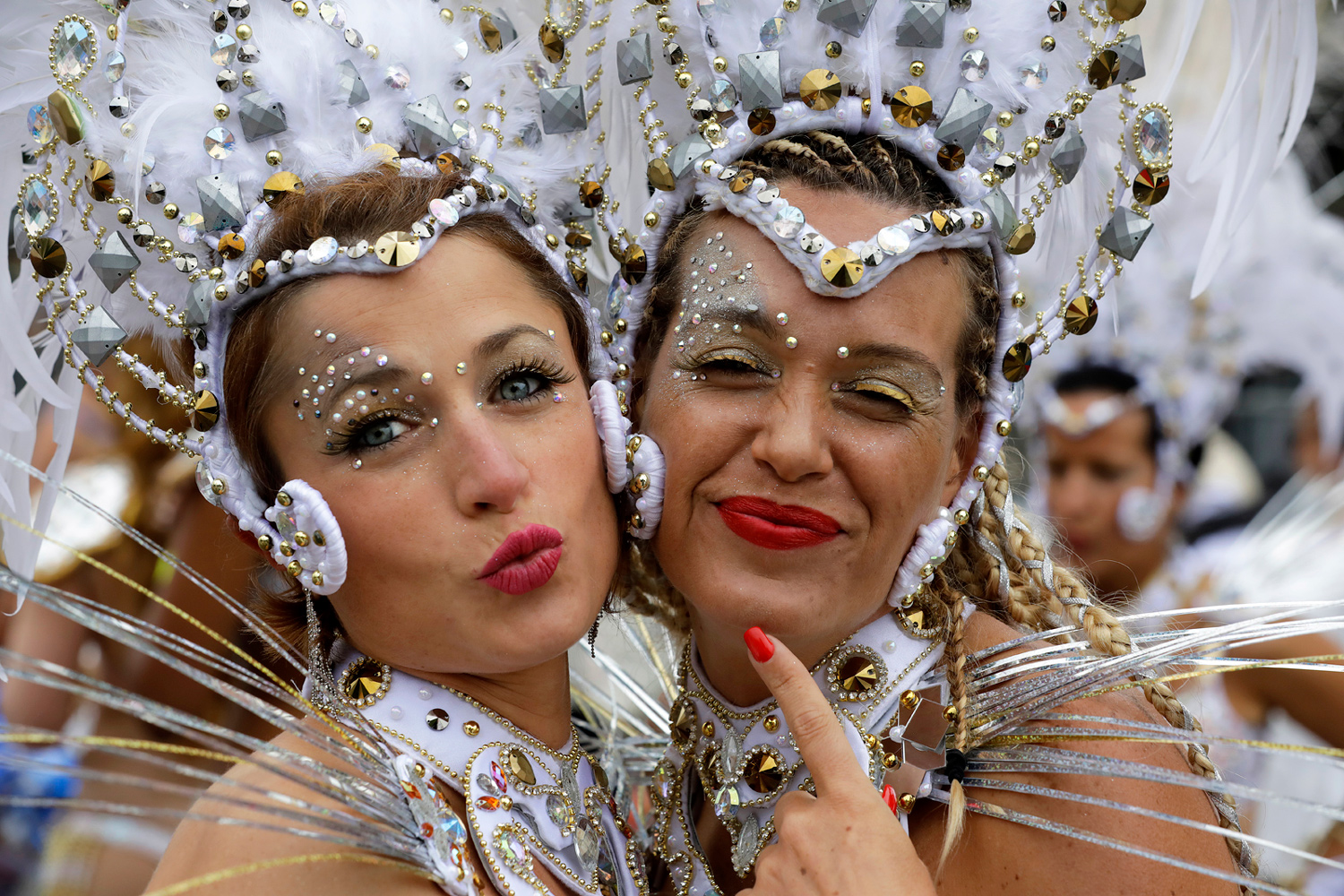 Deux danseuses souriantes posent ensemble dans des costumes blancs richement décorés.