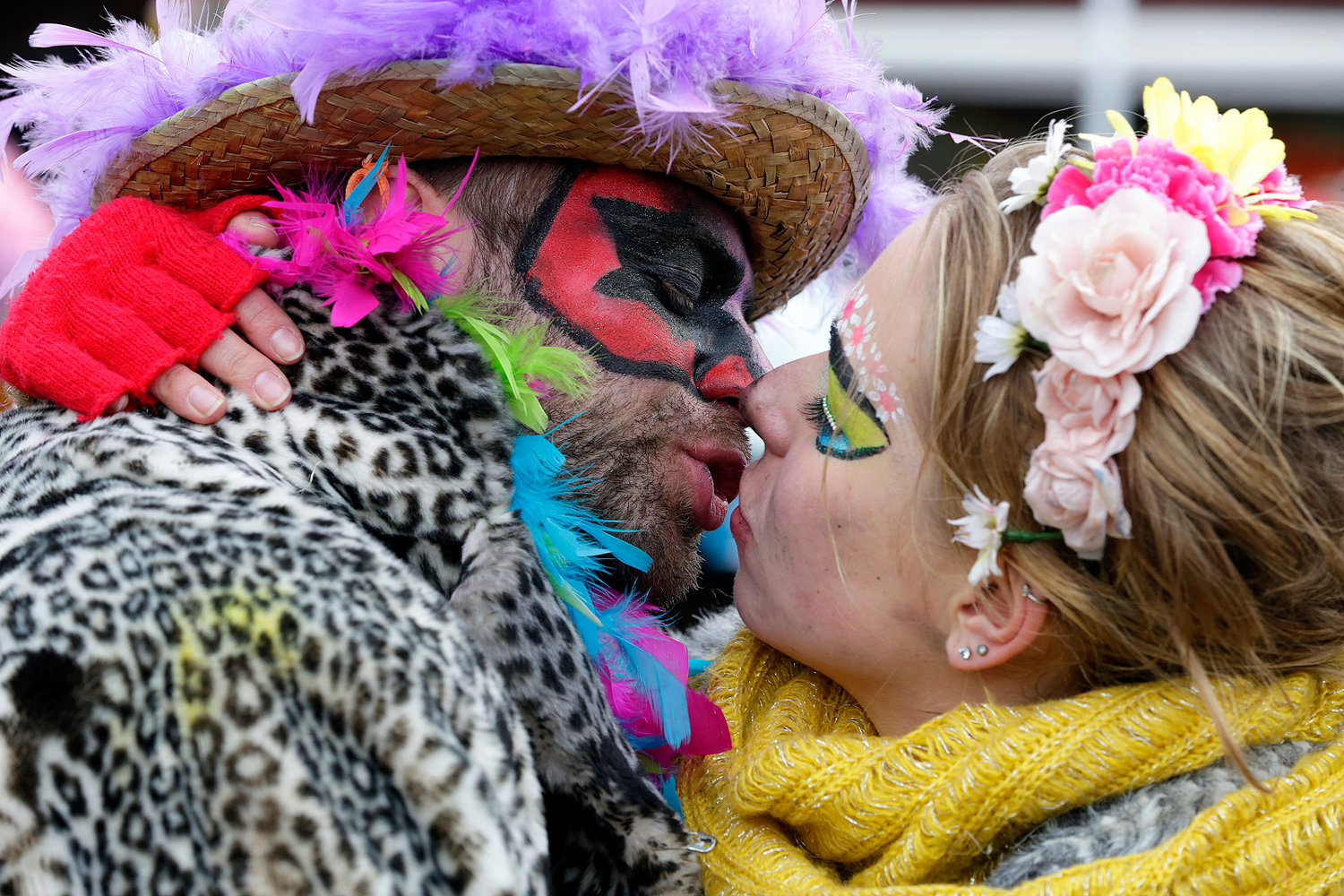 Un carnavaleux maquillé de noir et de rouge embrasse une carnavalière portant une couronne de fleurs, lors de la Bande de Bergues du Carnaval de Dunkerque.