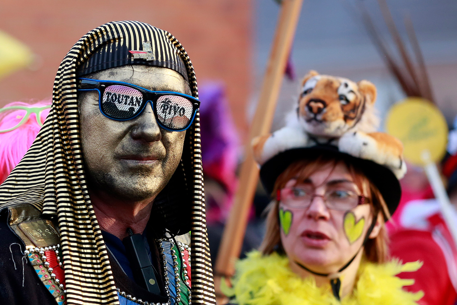 Portrait d'un carnavaleux portant une coiffe inspirée de l'Égypte antique, des lunettes fantaisie et un maquillage noir et blanc.